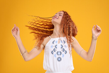 Beautiful young hippie woman dancing on orange background