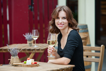 Beautiful young woman drinking white wine on the terrace of a restaurant