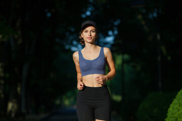 Athletic young woman in sportswear jogging in the park. Fitness and healthy lifestyle. Portrait of a beautiful young woman in sportswear outdoors. Sport fitness model caucasian ethnicity training outd