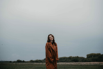 beautiful lonely woman in a brown coat in a field in autumn. Existential crisis and loneliness.