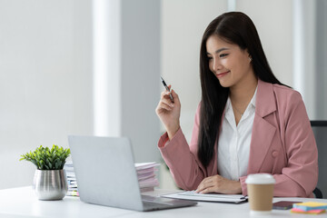 Confident and happy asian businesswoman using laptop computer to work on financial and marketing project in office.