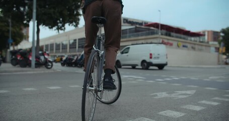 Urban city cyclist waits for green light on traffic crossing, perform trackstand on his bicycle. Busy city life and traffic. Commuter cyclist on the way to work or school