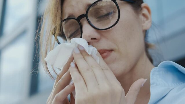 Close-up woman suffering seasonal allergy and rhinitis, sneezing to paper tissue