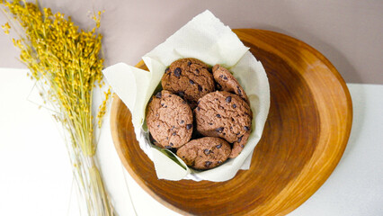 Chocolate chip cookies in a wicker basket on a wooden table