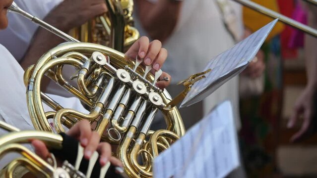 Artist playing the trombone at a parade, close look at the instrument and hands in a slow-motion clip.