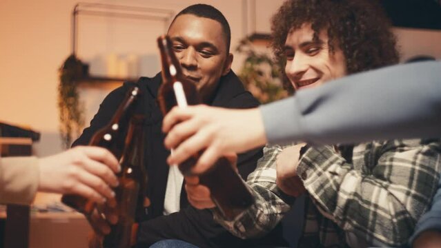Multiethnic friends celebrating graduation with beer, enjoying dorm party