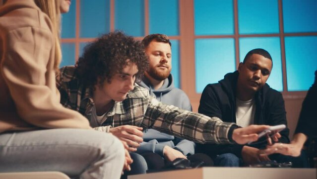 Group of multiethnic friends stacking smartphones on table, device-free party