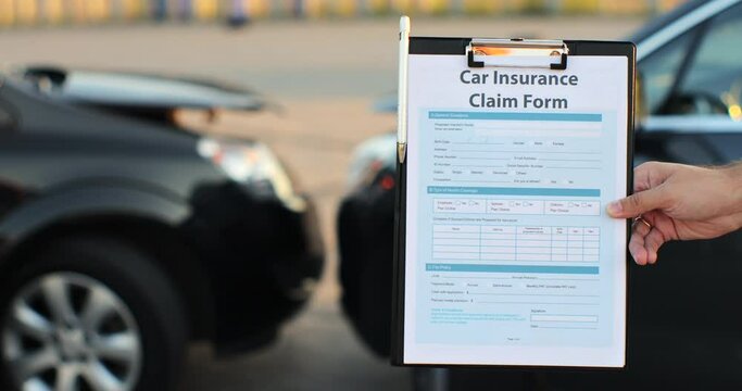 Close up of a man car insurance agent inspecting damaged car with insurance claim form. Insurance concept.