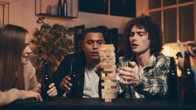 Relaxed multiracial friends playing leaning tower game and laughing, having fun