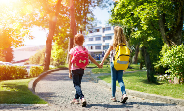 Students With Rucksacks Walking In The Park - Schoolgirls Return To School