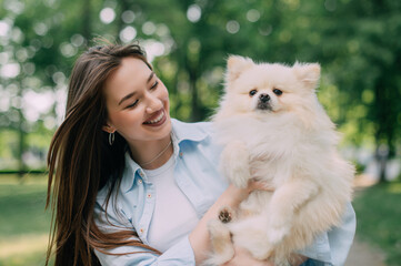 Portrait of a young woman with her dog. Pomeranian in the hands of his owner.