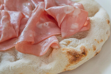 Macro close-up of 'Pinsa' with Italian mortadella.