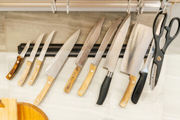 kitchen knives on a magnetic wall holder. hanging storage of iron knives in the house. different knives for cooking