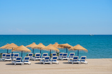 Beautiful sandy beach with palm tree umbrellas and sun loungers