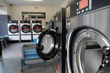 Close up of open wash machine in a public laundry for coin wash.