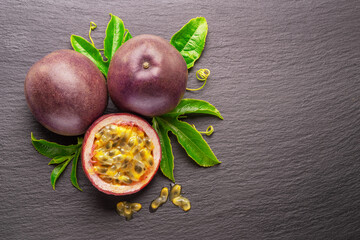 Dark purple passion fruits and half of maracuya fruit isolated on slate graphite gray background.