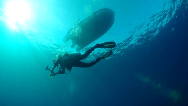 Scuba diver underwater. A silhouette of diver in clear blue water