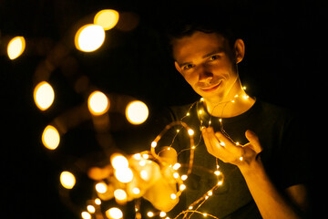 young guy at night holding glowing garlands in his hands, selective focus