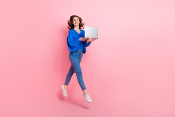 Full size profile portrait of excited nice girl jump use netbook empty space isolated on pink color background