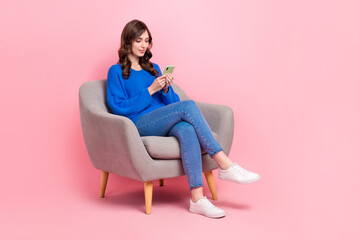 Full size photo of lovely young lady sit soft armchair hold device typing wear trendy blue garment...