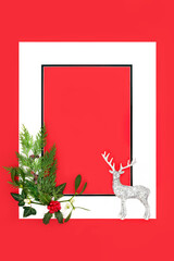 Christmas eve reindeer holly and winter greenery  background on red with white frame. Merry Christmas Noel Yule greeting card, gift tag, letter, menu, invitation.