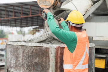 Construction workers pouring wet concrete by concrete bucket for building precast concrete wall at construction site