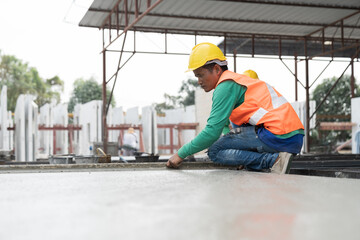 Asian male builder worker making levelling concrete floor to smooth at construction site. Construction worker uses long trowel spreading wet concrete pouring. Mason making smooth surface of concrete