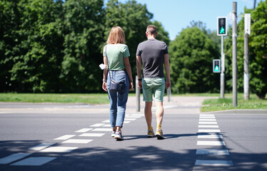 Man and woman cross the road at pedestrian crossing. Pedestrian safety and care on the roadway...