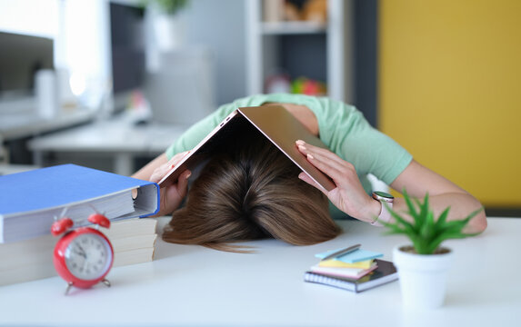 Tired young woman lies on table on head with laptop. Chronic fatigue at work concept - Powered by Adobe