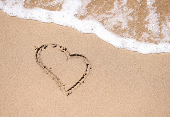 Drawn heart on wet sand next to sea. Romantic travel to the sea concept