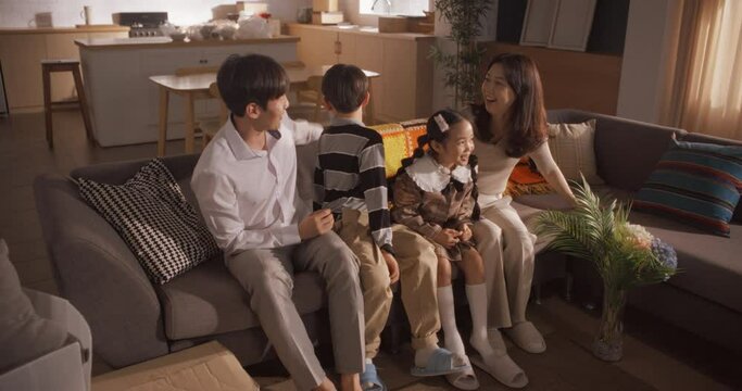 Family Moving in: Happy Young Korean Couple and Their Kids Sitting in Their Newly Purchased Apartment. Beautiful Family Happily Embracing, Discussing and Imagining How to Decorate Their New Home
