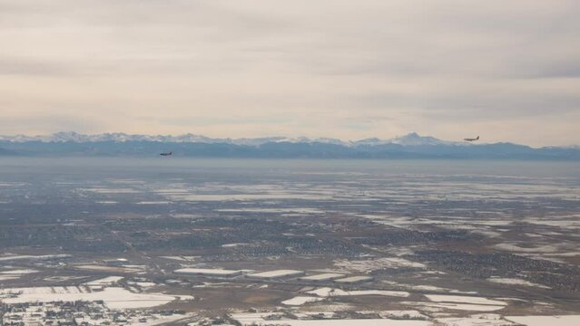 Two planes landing at Denver International airport with the Rocky Mountains in the background.  Shot in 4K
