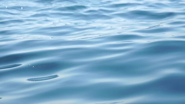 Sea water surface. Camera flies over the calm azure sea with volcanic rocky shores on background. Nobody. Holiday recreation concept. Abstract nautical summer ocean nature. Slow motion. Close up