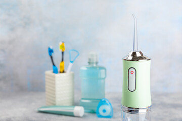 Electronic oral irrigator, toothbrush, paste, dental floss and mouthwash on a blue background. Dental tool for oral hygiene. Electric Interdental Cleaner. Dental water shower. Oral care concept.