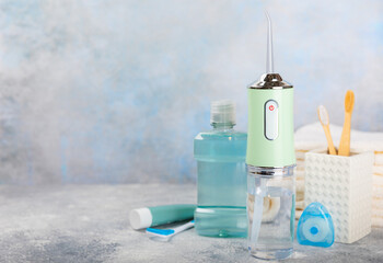 Electronic oral irrigator, toothbrush, paste, dental floss and mouthwash on a blue background. Dental tool for oral hygiene. Electric Interdental Cleaner. Dental water shower. Oral care concept.