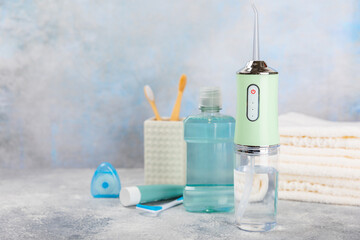 Electronic oral irrigator, toothbrush, paste, dental floss and mouthwash on a blue background....