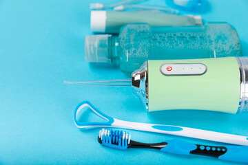 Electronic oral irrigator, toothbrush, paste, dental floss and mouthwash on a blue background. Dental tool for oral hygiene. Electric Interdental Cleaner. Dental water shower. Oral care concept.