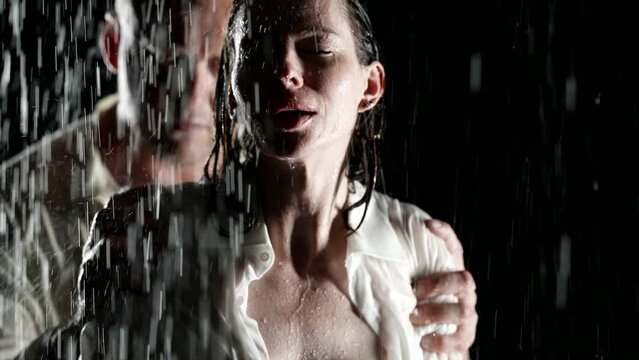aggressive man grabbing woman in night, portrait in rain in darkness, harassment or seduction