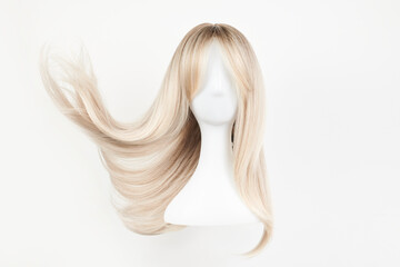 Natural looking blonde wig on white mannequin head. Long hair on the plastic wig holder isolated on...