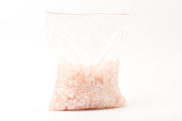 Chipped Himalayan pink salt stone in zip bag isolated on white background