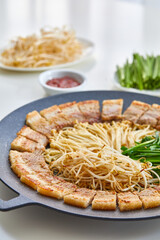 그리들위에 맛있게 구워진 벌집 삼겹살과 팽이버섯과 부추와 숙주나물