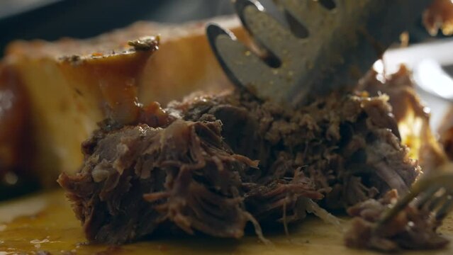 Macro preparation of food, Fork Pulling Apart Meat in Close-Up Culinary Scene. Shredding osso buco