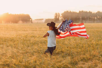 Woman with american flag on the field at sunset. Labor day concept.