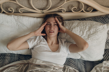 Young woman with headache flu ill sick disease cold at home indoor lying on bed