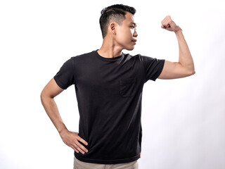 Naklejka premium A portrait of an Asian man wearing a black shirt, stretching and showcasing his arm muscles. Isolated with a white background.