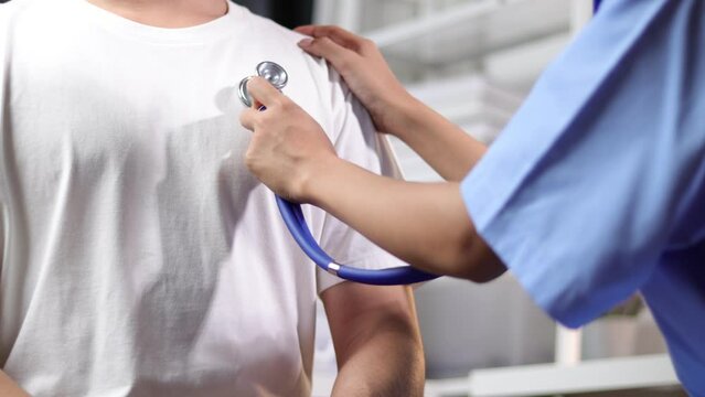 Doctor using stethoscope to diagnose and examine male patient in hospital examination room.
