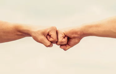 Foto op Plexiglas Teamwork and friendship. Partnership concept. Man giving fist bump. Bumping fists together. Fist Bump. Clash of two fists. Concept of confrontation, competition © Yevhen
