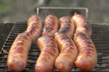 Grilled sausages. Cook man preparing grilling food bbq. Barbecue with smoke, flame outdoors. Tasty...