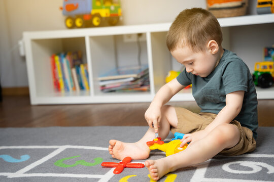 A little toddler boy 2,5 years is playing with a toy helicopter, assembling and disassembling it. Educational toys for kids. Children's room in home. Indoors