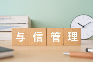 与信管理と書かれたブロックが置かれたデスク